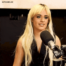 a woman with blonde hair stands in front of a microphone that says pow 106 fm
