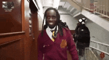 a man in a maroon sweater and tie is walking down stairs