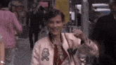 a woman wearing a pink jacket with a skull and crossbones patch on it is walking down a street .