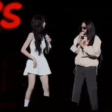 two women standing next to each other on a stage holding microphones