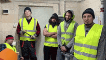 a group of men wearing neon yellow vests are standing in a room