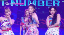 a group of girls are dancing on a stage with the word number behind them