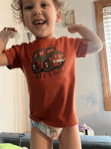 a little boy wearing a red shirt that says it 's go flexes his muscles