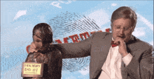 a man in a suit holds a statue of a man with a sign that says den perry did it