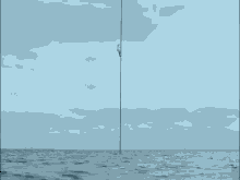 a pole in the middle of the ocean with a cloudy sky in the background
