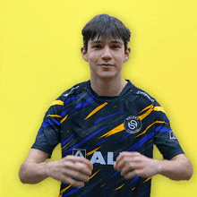 a young man wearing a blue and yellow shirt that says ' aal ' on it