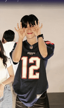 a man wearing a patriots jersey is making a funny face