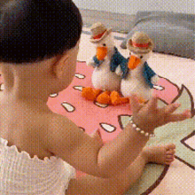 a baby playing with stuffed ducks on a donut