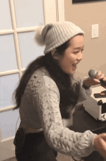 a woman is singing into a microphone while wearing a hat .