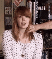 a woman in a polka dot shirt is being touched by a man in front of a rock and roll bookshelf