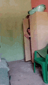 a person peeking out from behind a closet with a green chair