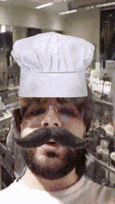 a man with a beard and mustache wears a chef 's hat