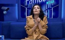a woman is sitting on a blue couch in front of a famous mexico sign