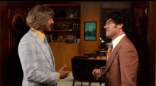 two men in suits are shaking hands in a room