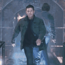 a man wearing a green jacket is walking through a tunnel .