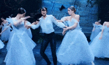 a group of women in blue and white dresses are dancing