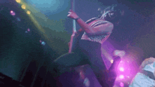a man is playing a guitar on stage with purple lights behind him