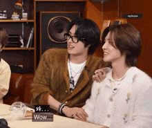 two people are sitting at a table and one of them is talking about wow