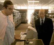 a man in a suit stands next to a woman in a pink sweater in a library