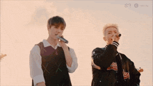 a person is singing into a microphone while another person plays a flute in the background .