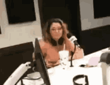 a woman is sitting at a table in front of a microphone in a radio studio .