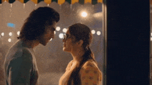 a man and a woman are kissing in front of a window .