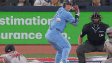 a blue jays player swings at a ball in front of an ad for estimation insurance