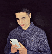 a man in a blue shirt is looking at a cell phone