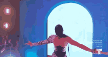 a woman is standing in front of a blue wall with her arms outstretched