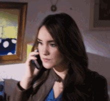 a woman is talking on a cell phone in front of a framed picture