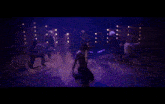 a woman sits in a chair in a dark room surrounded by dancers