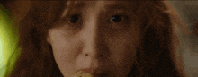a close up of a woman 's face with red hair eating corn on the cob