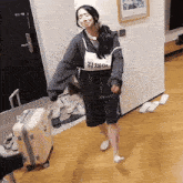 a woman wearing a name tag that says kim on it stands next to a suitcase