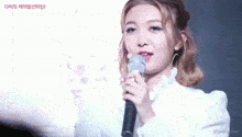 a woman in a white dress is singing into a microphone