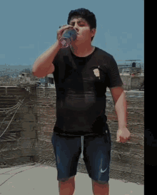 a man drinking from a purple bottle that says ' coca-cola ' on it
