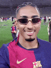 a man wearing sunglasses and a nike shirt is smiling