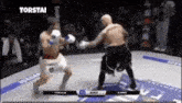 two men are fighting in a boxing ring and one of them is throwing a punch .