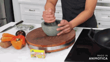 a person is using a mortar and pestle on a wooden cutting board in a kitchen