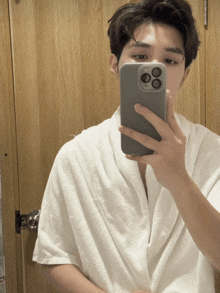 a man in a white robe is taking a picture of himself in a mirror