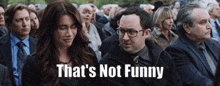 a man and a woman are sitting in a crowd with the words that 's not funny on the bottom