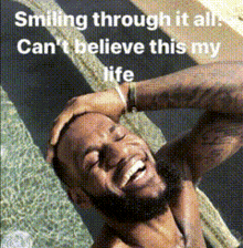 a man with a beard is smiling with the words smiling through it all can 't believe this my life below him