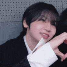 a close up of a person making a heart shape with their hands