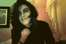 a woman with a scar on her face is smiling in a room with a picture on the wall .