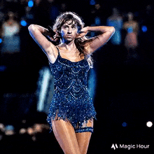 a woman in a blue dress is standing on a stage with her hands on her head .