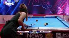 a woman is playing pool on a screen that says i news