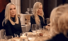 two women sit at a table with wine glasses