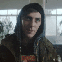 a man wearing a hooded jacket and a doom patrol shirt