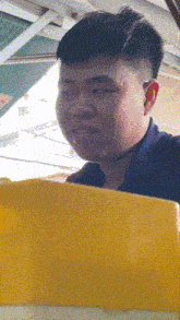 a man in a blue shirt is looking at something in a yellow box