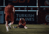 two soccer players on a field with a turkish airlines banner behind them