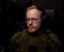 a man with glasses and headphones is sitting in a chair .
